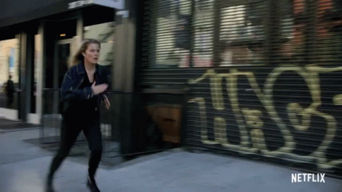 Woman Running Past Netflix Building GIF