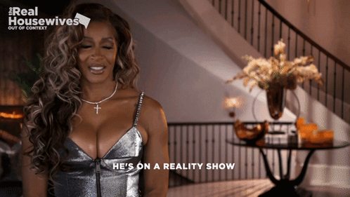 Woman Saying He's On Reality Show In Silver Dress GIF