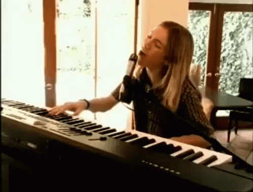 Woman Singing Into Microphone and Playing Keyboard
