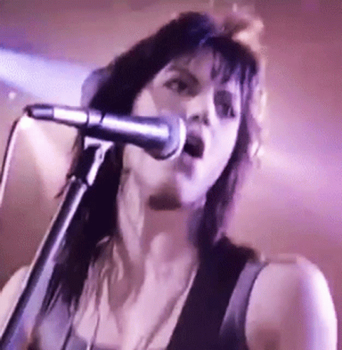 Woman Singing Into Microphone in Dark Room