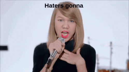 Woman Singing Into Microphone in Front of Band Saying Hate