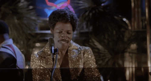 Woman Singing Into Microphone in Front of Glass Wall