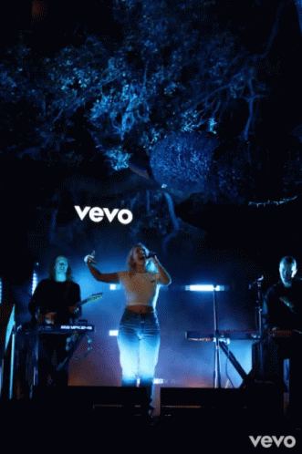 Woman Singing Into Microphone in Front of Vevo Sign