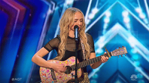 Woman Singing Into Microphone Playing Guitar NBC