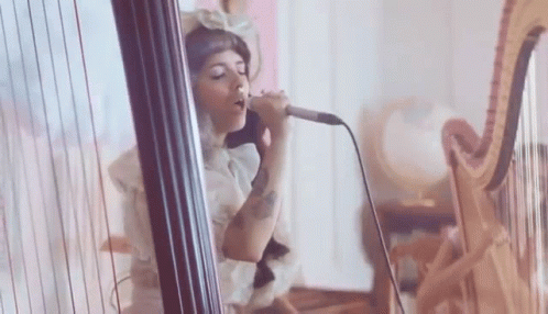 Woman Singing Into Microphone Playing Harp