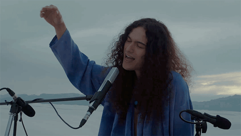 Woman Singing Into Microphone With Fist in Air