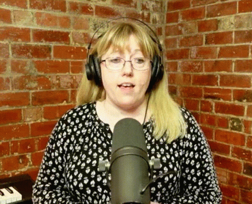 Woman Singing into Microphone with Glasses and Headphones