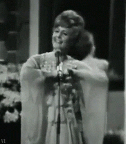 Woman Singing Into Microphone With Letters VE