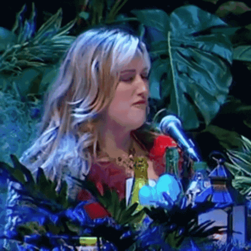 Woman Singing Into Microphone With Plants