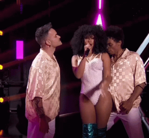 Woman Singing Into Microphone with Two Men Watching