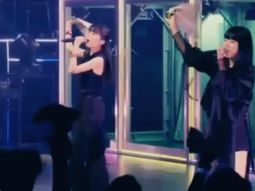 Woman Singing into Microphone with Woman Behind