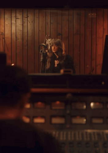 Woman Singing Into Microphone With X Necklace