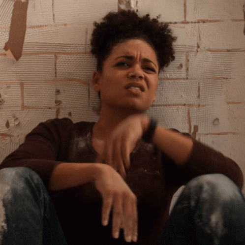Woman Sitting Against Brick Wall GIF
