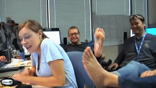 Woman Sitting at Desk with Feet on Man