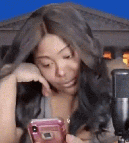 Woman Sitting at Microphone Looking at Phone