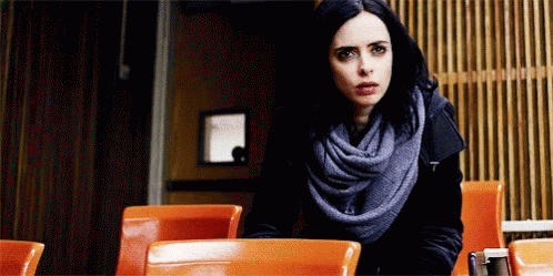 Woman Sitting at Restaurant Table Wearing Scarf and Black Jacket