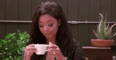 Woman Sitting at Table Drinking Cup