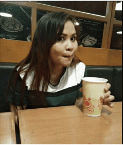 Woman Sitting at Table Holding Cup