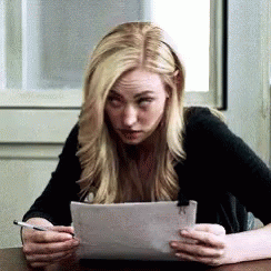 Woman Sitting at Table Holding Paper