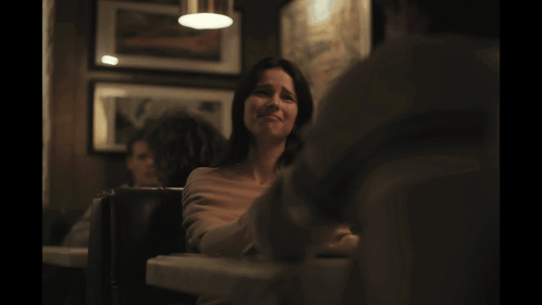 Woman Sitting at Table in Dark Room