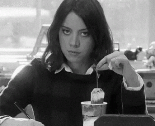 Woman Sitting at Table with Coffee and Tea Bag