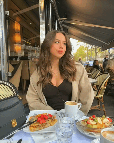 Woman Sitting at Table with Food and Coffee