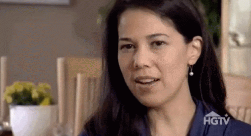 Woman Sitting At Table With HGTV Logo On Shirt GIF