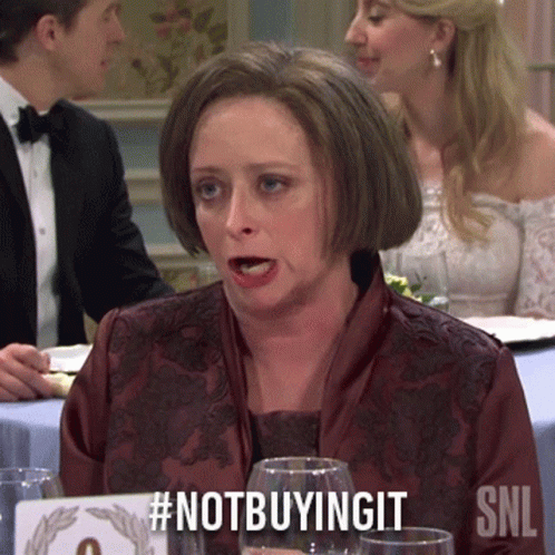 Woman Sitting at Table with #notbuyingit Sign