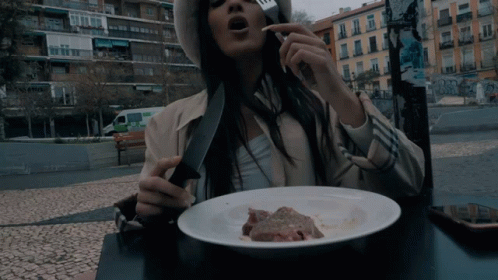 Woman Sitting At Table With Plate Of Food And Knife GIF
