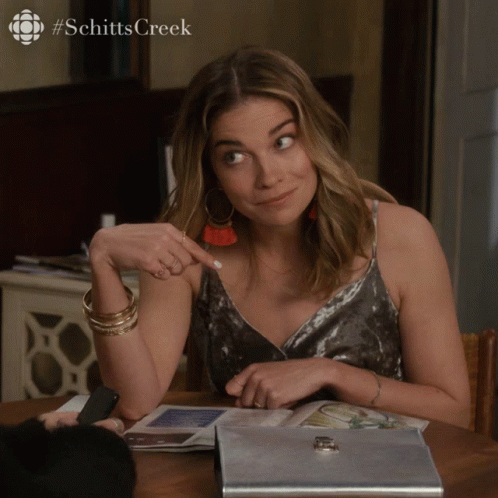 Woman Sitting At Table With Schitts Creek Logo GIF