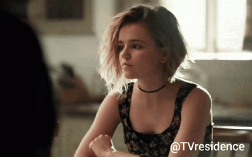 Woman Sitting At Table With TV Residence Watermark GIF