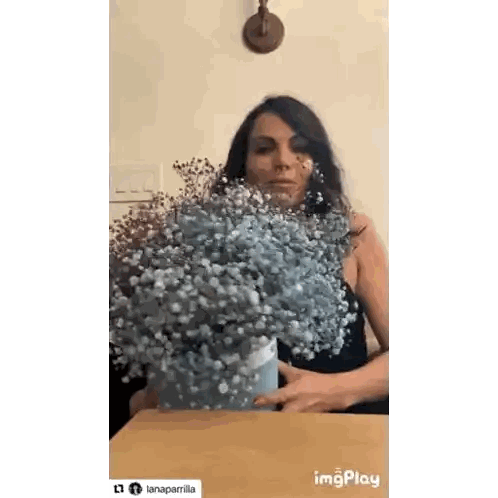Woman Sitting at Table With Vase of Baby's Breath