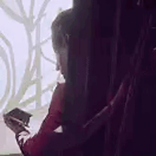 Woman Sitting By Window Holding Pen And Phone GIF