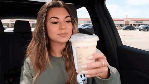 Woman Sitting in Car Holding Coffee