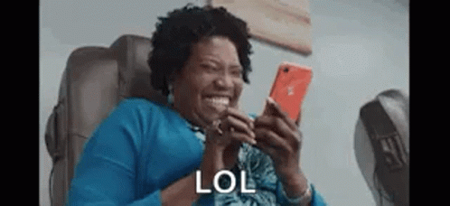 Woman Sitting in Chair Laughing at Phone