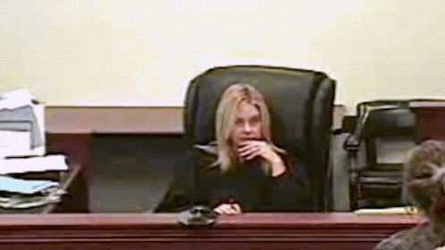 Woman Sitting In Courtroom Hand On Chin GIF