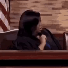 Woman Sitting in Courtroom Holding Microphone
