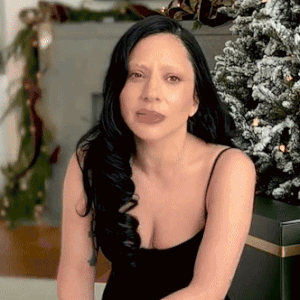 Woman Sitting in Front of Christmas Tree in Black Dress