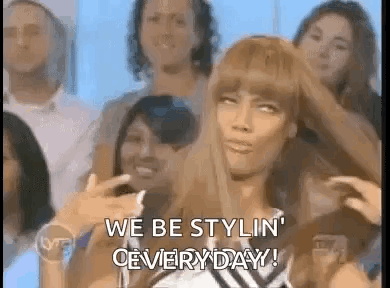 Woman Sitting In Front Of Crowd With Hair In Hand GIF