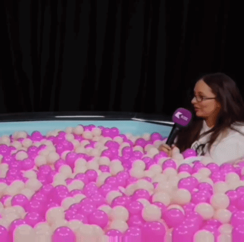 Woman Sitting In Pink And White Ball Pit GIF