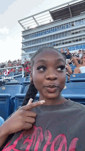 Woman Sitting in Stands Pointing at Herself