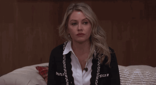 Woman Sitting On Bed In Black Cardigan With Pearls GIF