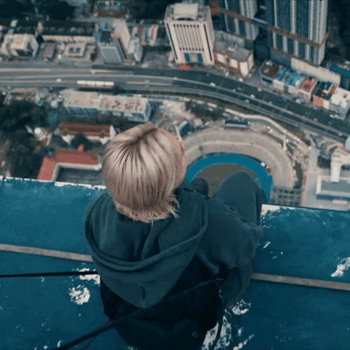 Woman Sitting On Building Edge Overlooking City GIF