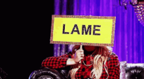 Woman Sitting on Couch Holding Lame Sign