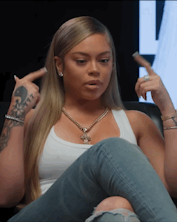 Woman Sitting On Couch In White Tank Top And Blue Jeans GIF
