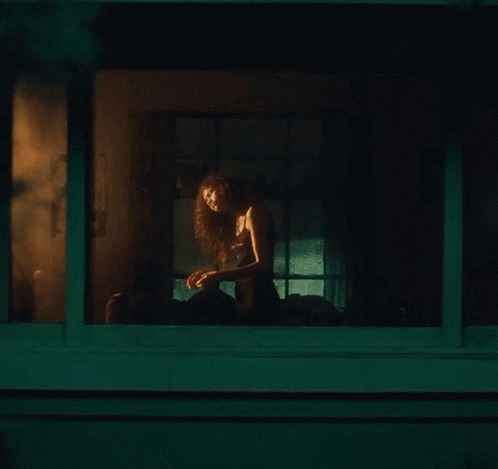Woman Sitting on Porch Looking Out Window at Night