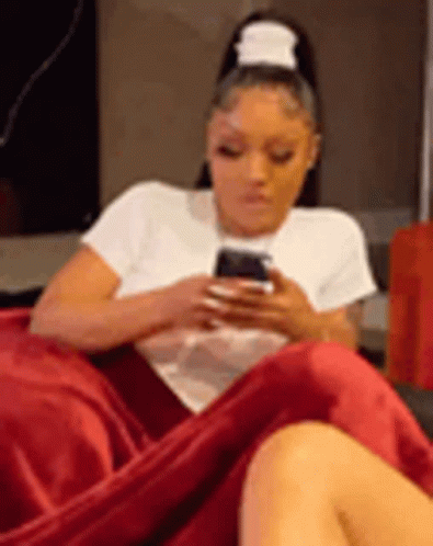 Woman Sitting on Red Blanket Looking at Phone