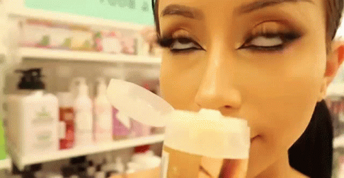 Woman Smelling Bottle Of Lotion In Store GIF