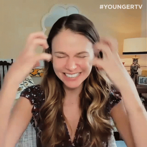 Woman Smiling and Covering Ears in Younger TV Shirt