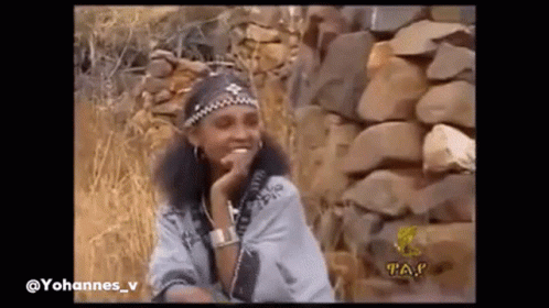 Woman Smiling Beside Stone Wall GIF